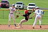 Base runner slides into a base while two fielders watch during a baseball game.