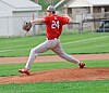 Baseball pitcher in a red jersey winds up and throws from the mound on a field.