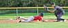 Baseball player in red slides toward home plate while catcher in black attempts a tag.