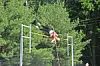 Pole vaulter in midair clearing the bar outdoors near trees.