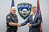 A police officer shakes hands with a man in a suit beside a Mount Vernon Police Department logo.
