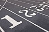 Close-up of a track with white lane numbers and dividing lines on a dark surface.