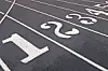 Close-up of a track with white lane numbers and dividing lines on a dark surface.