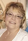 Smiling woman wearing glasses and a light-colored top, shown indoors in a screenshot.