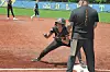 Youth softball player slides into a base during a game with a coach nearby.