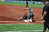 A softball catcher tags a sliding runner at home plate during a game.