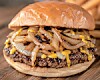 Close-up of a cheeseburger with grilled onions and melted cheese on a wooden board.