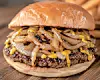 Close-up of a cheeseburger with grilled onions and melted cheese on a wooden board.