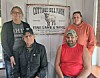 Four people pose indoors in front of a Cottage Hill Farm sign on the wall.