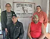 Four people pose indoors in front of a Cottage Hill Farm sign on the wall.
