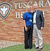 Two people posing beside a Tuscarora Health sign on a brick wall.