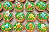 Rows of colorful decorated cookies with bird and flower designs on a tray.