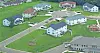Aerial view of suburban homes with lawns, driveways, and roads in a residential neighborhood.