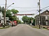 Fire truck and responders on a residential street with houses and a banner overhead.