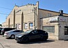 Beige brick commercial building with a sign, glass block windows, and parked cars in front.