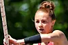 Female athlete holding a pole outdoors with a focused expression.