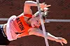 Athlete in orange Princeton uniform arches over a high jump bar during a track and field competition.