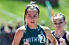 Runner in a Smithville uniform competes on a track with another athlete behind her.