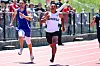 Two sprinters run on a track, with one wearing a Smithville jersey.