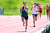 Two runners compete on a red track, with one athlete in front and another close behind.