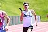 Runner in a white Smithville jersey sprints on a track holding a baton.