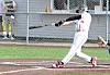 Baseball player in white uniform swings a bat during a game.