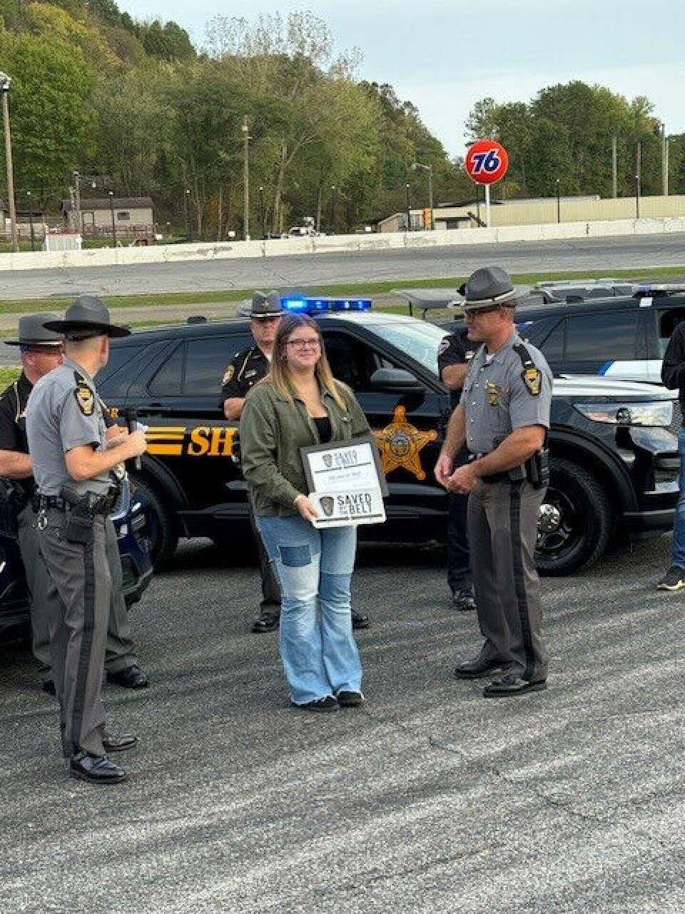 Submitted PhotoOliviaa Hull (center) is shown holding her Saved by the Belt license plate and certificate. At left is Lt. Johnnie H. Maier of the New Philadelphia Post of the Ohio State Patrol and at right is Staff Lt. Scott Louive. Both were involved in a ceremony at Midvale Speedway that recognized Hull and two Tuscarawas County residents for being safety conscious.