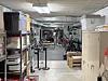 A cluttered room with shelves, cabinets, exercise equipment, benches, and stored items.