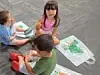 Three young children sit on a carpet with colorful activity mats and toys.