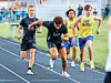 Track athletes sprinting from the starting line during a relay race.