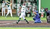Baseball batter swings at a pitch while the catcher crouches and the umpire stands nearby.