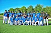 Youth baseball team in blue uniforms poses on a field with coaches at the side.