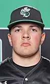 Close-up portrait of a baseball player wearing a black cap with a green logo and a black jersey.