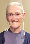 Close-up portrait of an older woman smiling and wearing glasses against a plain background.