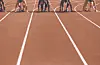 Sprinters crouch in starting blocks on a red running track before a race.