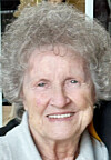 Close-up of an elderly woman smiling indoors.