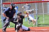 Softball pitcher throws a pitch with catcher and umpire at home plate.