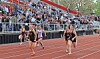 Track athletes sprint on a stadium track with a crowd watching from the bleachers.