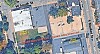 Aerial view of buildings, parked cars, trees, and a street intersection with painted road labels.