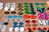 Rows of colorful buttons laid out on a table in a close-up view.