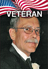 Portrait of an older man in a suit below an American flag graphic and the word 'VETERAN.'
