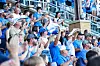 Crowd of baseball fans in blue cheering in stadium seats.