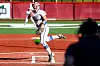 Softball pitcher throwing a ball on a red infield during a game.