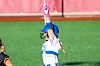 Softball player in white uniform raises a pink glove on a green field.