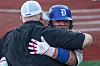 Two baseball players embrace on the field, one in a blue helmet and batting gloves.