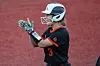 Softball player in black uniform and white helmet clapping on a red field background.
