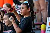 A young spectator with face paint holds a red bottle while sitting in the stands.