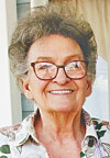 Smiling older woman wearing glasses in a close-up indoor portrait.