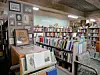Bookshelves filled with books in a room with framed portraits and display cases.
