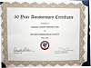 Framed 50 Year Anniversary Certificate with signatures and a circular seal on a patterned background.